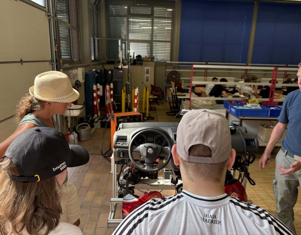 Personen vor einer Fahrerkonsole in einer Fertigungshalle