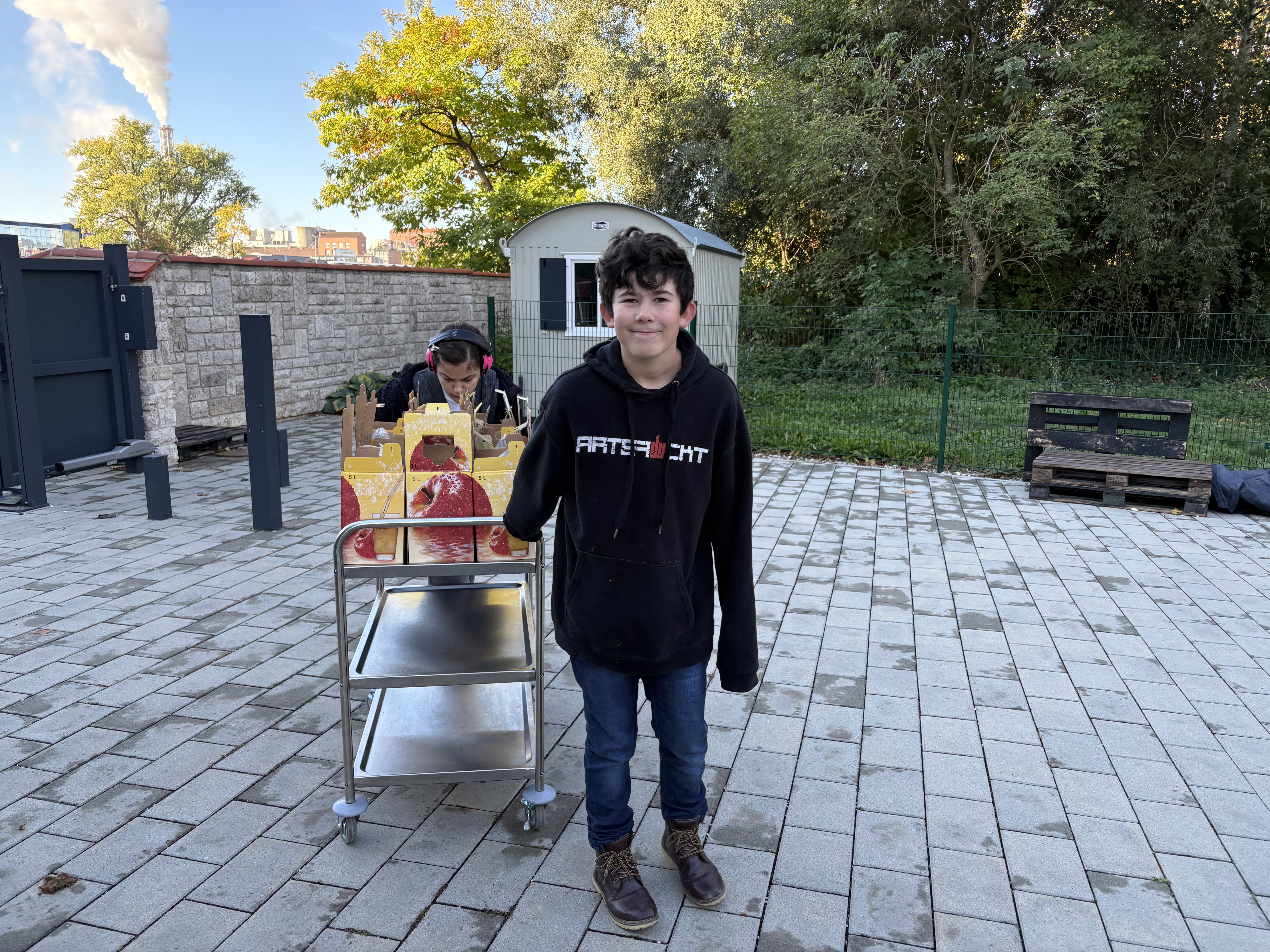 Foto: Ein Schüler und eine Schülerin schieben einen Wagen mit Apfelsaftkartons