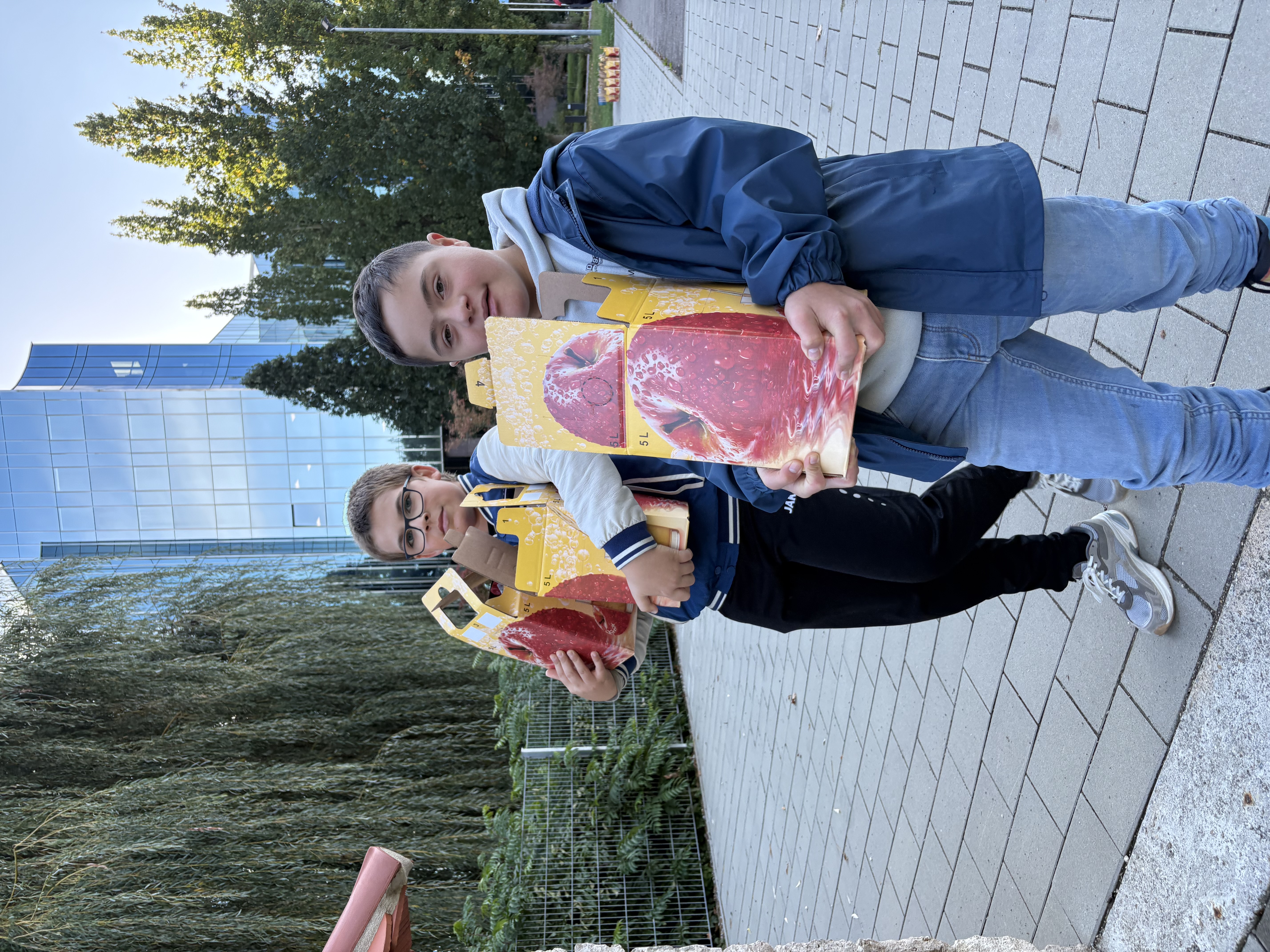 Foto: Zwei Schüler tragen Apfelsaftkartons