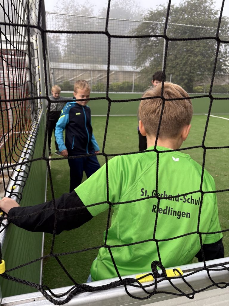 Schüler spielen gegeneinander Fußball auf einem Soccer- Court